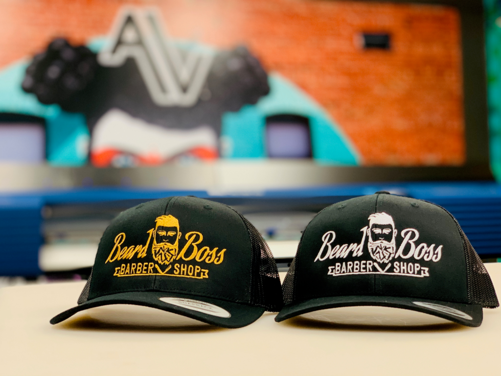 Two Beard Boss Barbershop hats on a table at the Rockwall location.